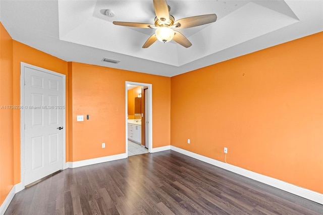 unfurnished room featuring a tray ceiling, hardwood / wood-style flooring, and ceiling fan