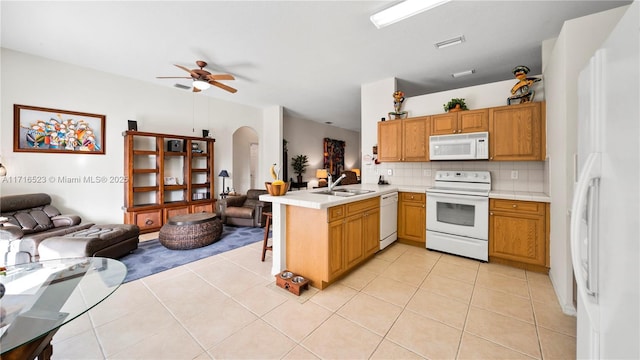 kitchen with sink, white appliances, light tile patterned flooring, decorative backsplash, and kitchen peninsula