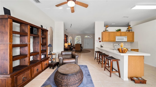 living room featuring sink, ceiling fan, and light tile patterned flooring