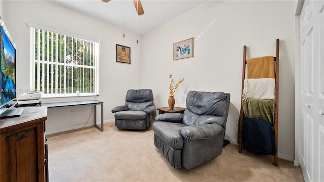 living area with light carpet and ceiling fan