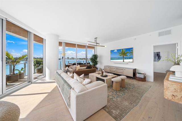 living room with light hardwood / wood-style flooring, expansive windows, and a chandelier