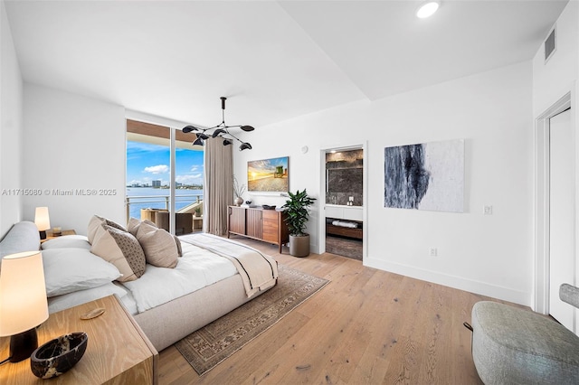 bedroom featuring access to outside, a water view, ceiling fan with notable chandelier, and light wood-type flooring