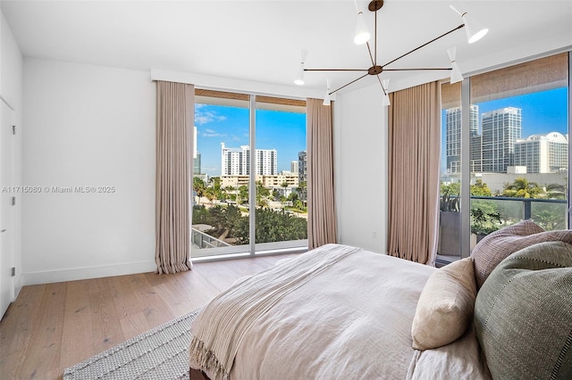 bedroom featuring multiple windows, a chandelier, light hardwood / wood-style flooring, and floor to ceiling windows