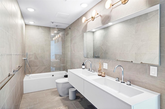 full bathroom with tiled shower / bath combo, tile patterned floors, toilet, vanity, and tile walls