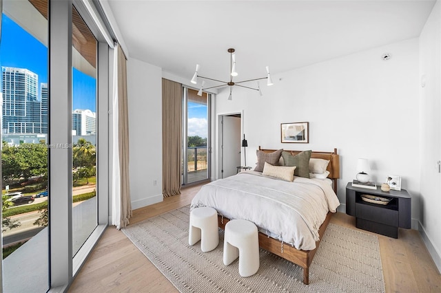 bedroom featuring access to outside, light hardwood / wood-style flooring, and a chandelier