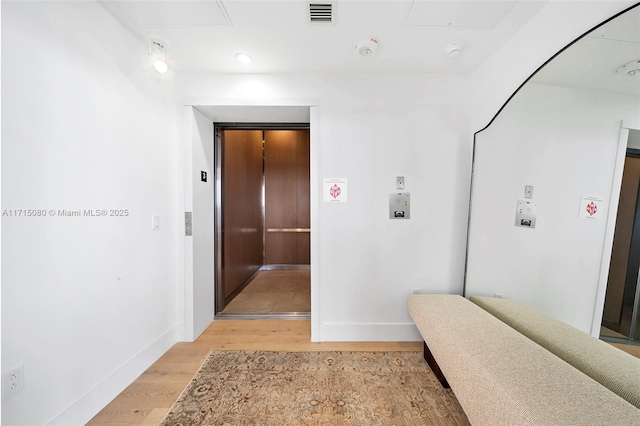 hall featuring light wood-type flooring and elevator