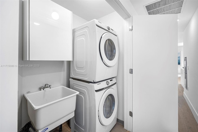 laundry room featuring stacked washing maching and dryer and sink