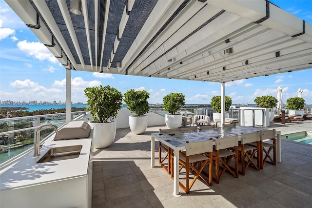 view of patio / terrace featuring sink, a water view, and a pool