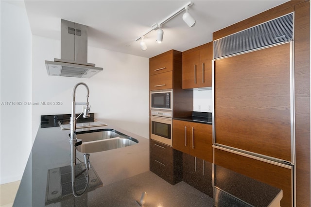 kitchen with ventilation hood, built in appliances, sink, and rail lighting