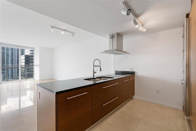 kitchen with dark brown cabinetry, floor to ceiling windows, sink, wall chimney range hood, and kitchen peninsula