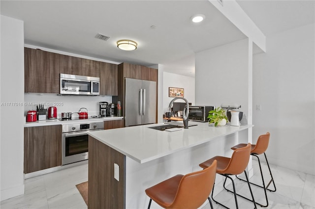 kitchen with appliances with stainless steel finishes, sink, a breakfast bar area, and kitchen peninsula