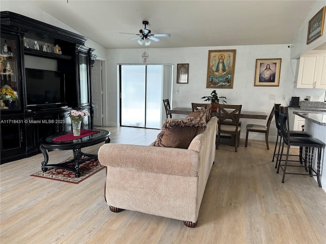 living room featuring ceiling fan, vaulted ceiling, and light hardwood / wood-style flooring