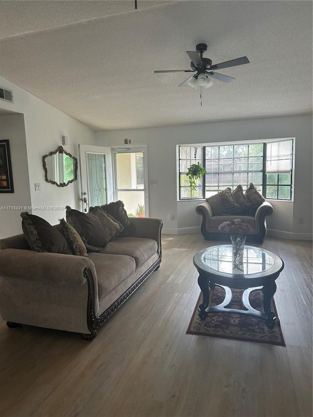 living room featuring hardwood / wood-style floors, ceiling fan, and a textured ceiling