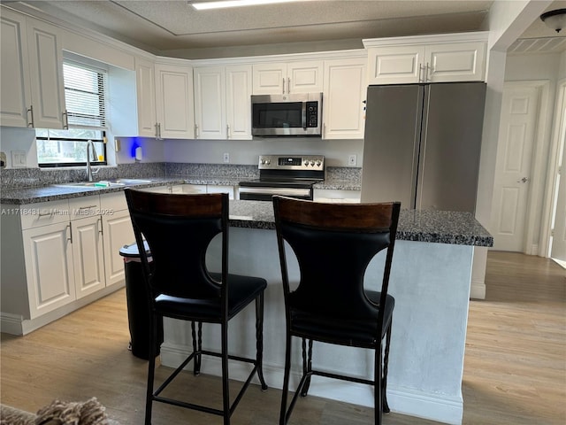 kitchen with a center island, white cabinets, stainless steel appliances, and sink