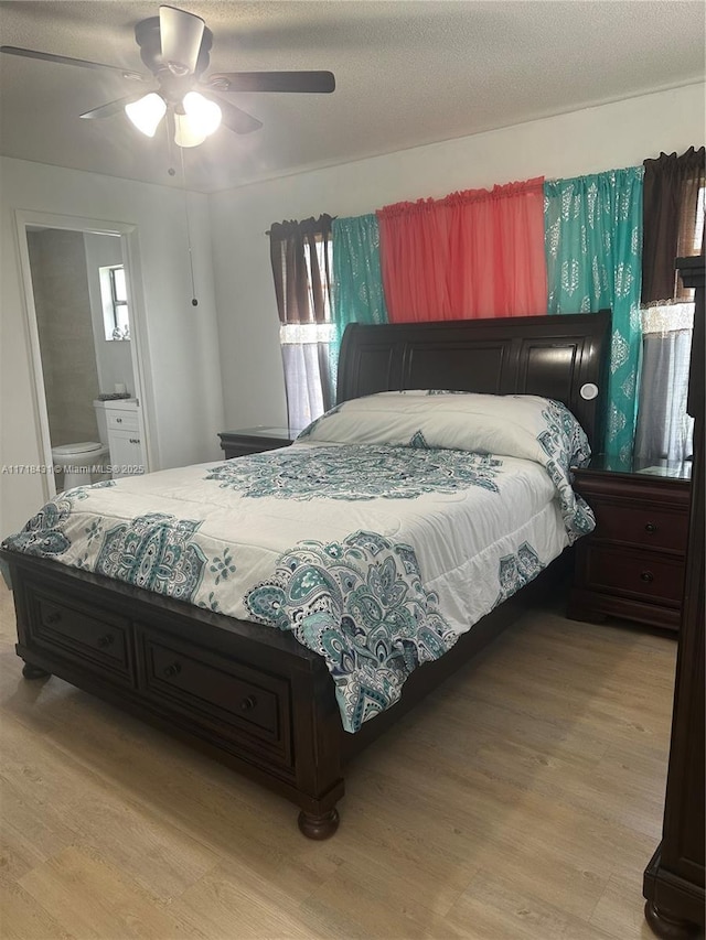 bedroom with multiple windows, ensuite bathroom, light hardwood / wood-style flooring, and ceiling fan