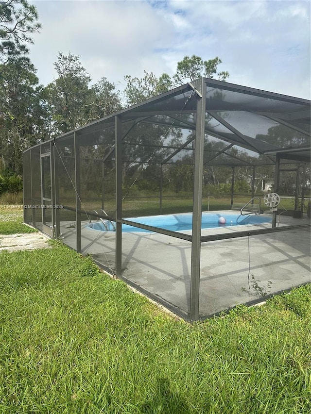 view of pool featuring a lanai and a lawn