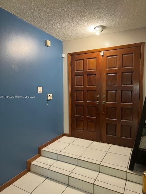 entryway with light tile patterned flooring and a textured ceiling