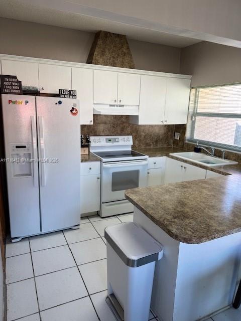 kitchen with white appliances, backsplash, sink, light tile patterned flooring, and white cabinetry