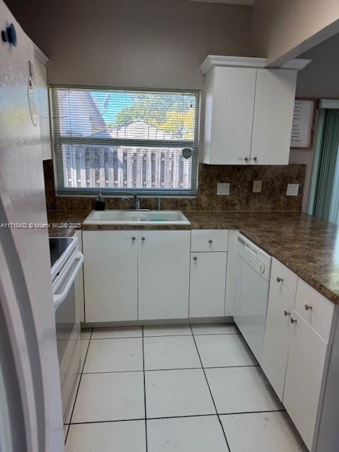 kitchen featuring white cabinetry, dishwasher, sink, light tile patterned floors, and range