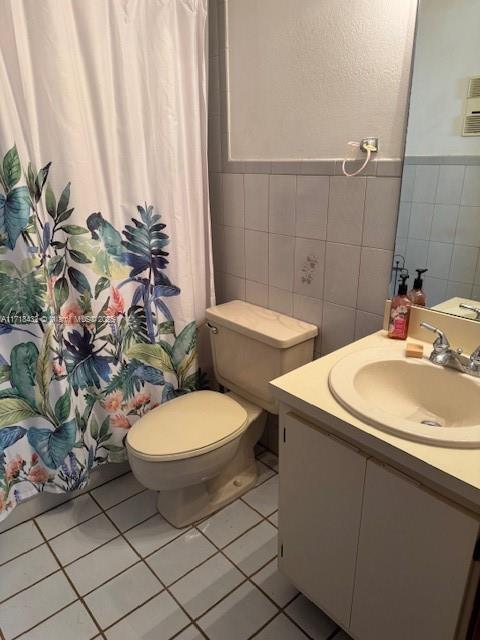 bathroom with tile patterned floors, toilet, vanity, tile walls, and a shower with shower curtain