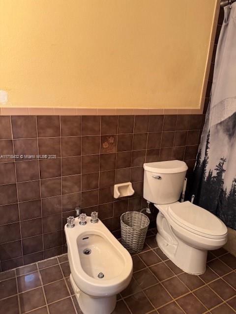 bathroom featuring tile patterned flooring, a bidet, and tile walls