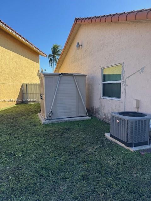 exterior space with central AC and a yard