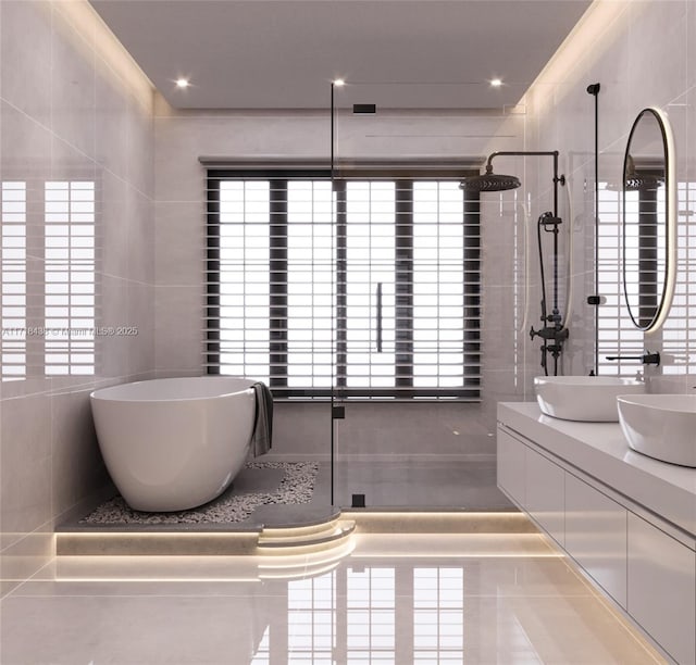 bathroom with shower with separate bathtub, vanity, tile patterned floors, and tile walls