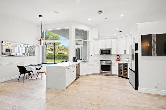 kitchen featuring appliances with stainless steel finishes, backsplash, sink, pendant lighting, and white cabinets