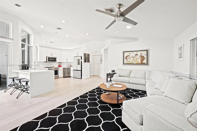 living room featuring ceiling fan, vaulted ceiling, and light wood-type flooring