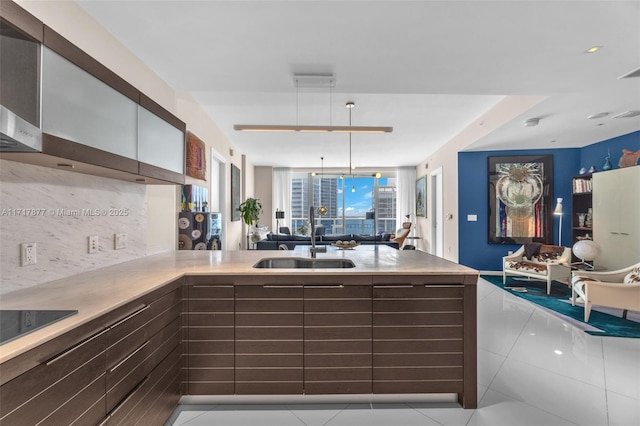 kitchen featuring open floor plan, backsplash, a peninsula, and a sink