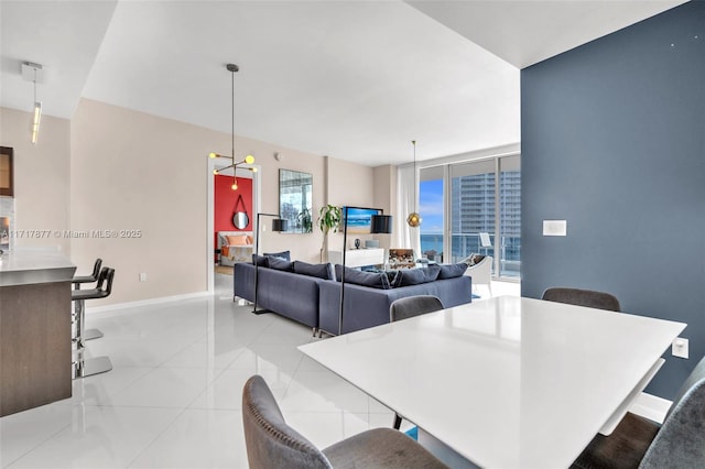 dining space with a wall of windows, light tile patterned flooring, and baseboards