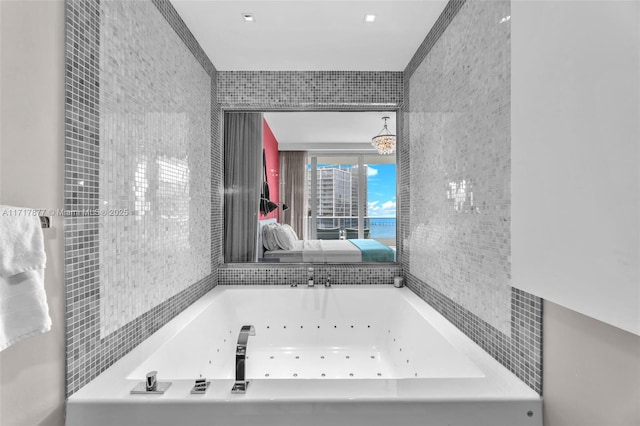 bathroom featuring a tub with jets and tile walls