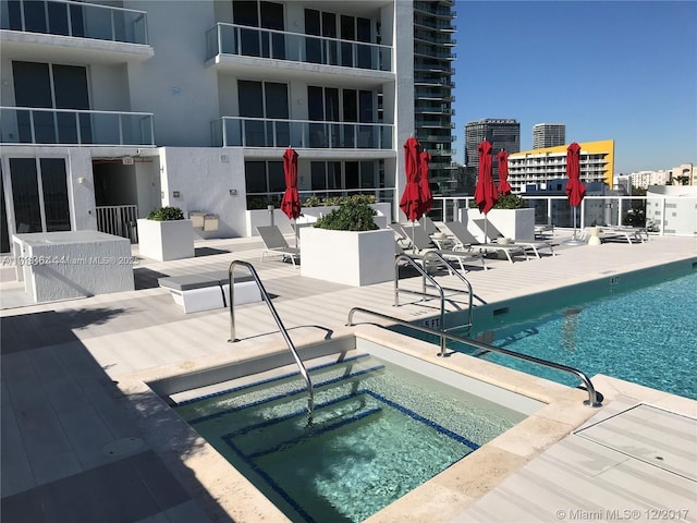 view of swimming pool with a hot tub and a patio