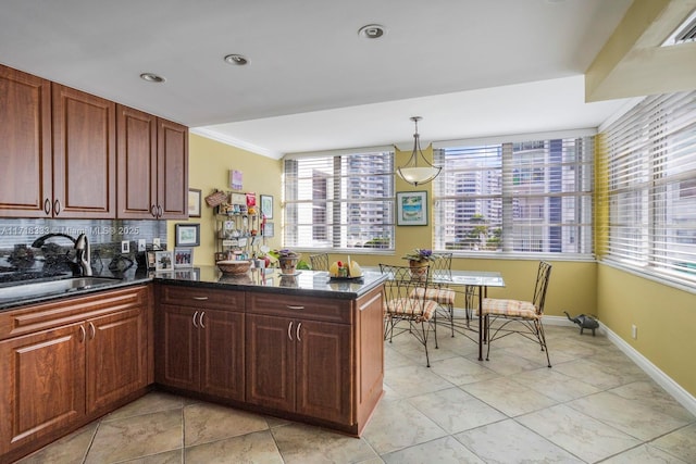 kitchen with kitchen peninsula, decorative backsplash, crown molding, sink, and hanging light fixtures