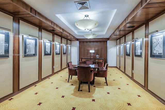 dining room featuring light carpet and a raised ceiling