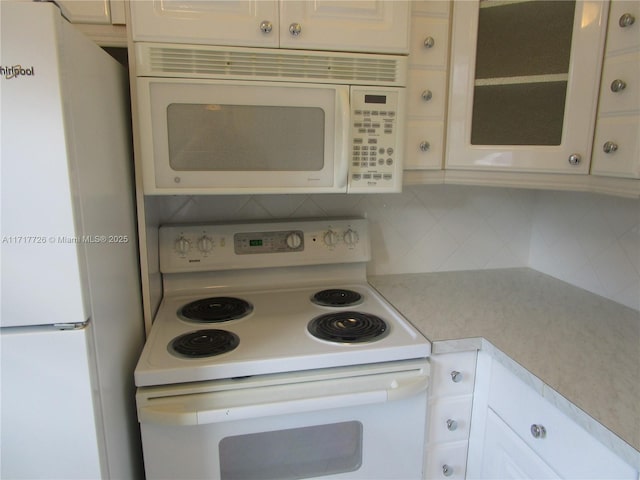 kitchen with decorative backsplash, white cabinetry, and white appliances