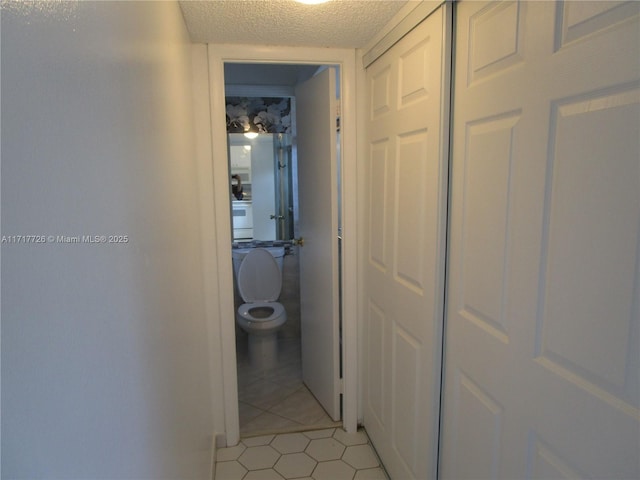 corridor featuring light tile patterned flooring and a textured ceiling