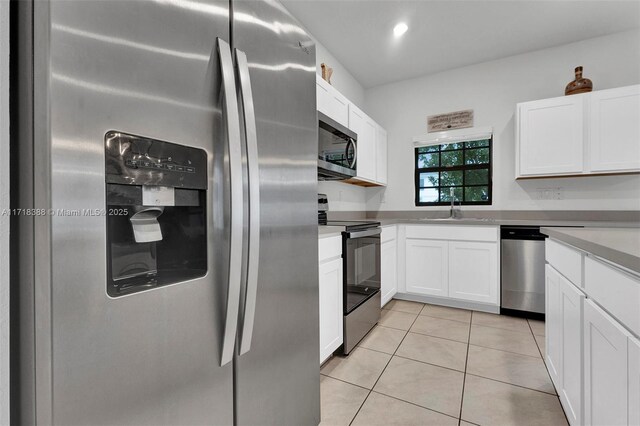 kitchen featuring appliances with stainless steel finishes, light tile patterned floors, white cabinetry, and sink