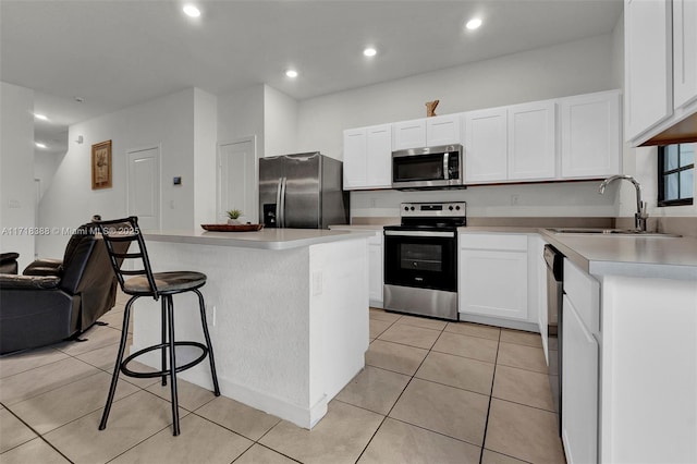 kitchen with a center island, white cabinets, sink, light tile patterned floors, and stainless steel appliances