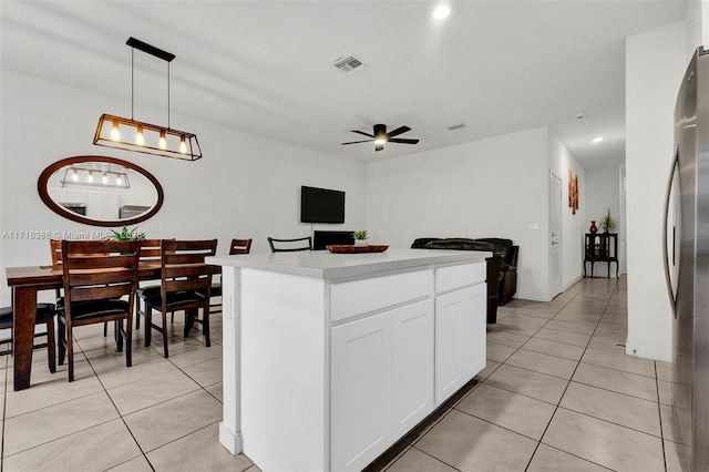 kitchen with ceiling fan, white cabinetry, a kitchen island, hanging light fixtures, and stainless steel refrigerator