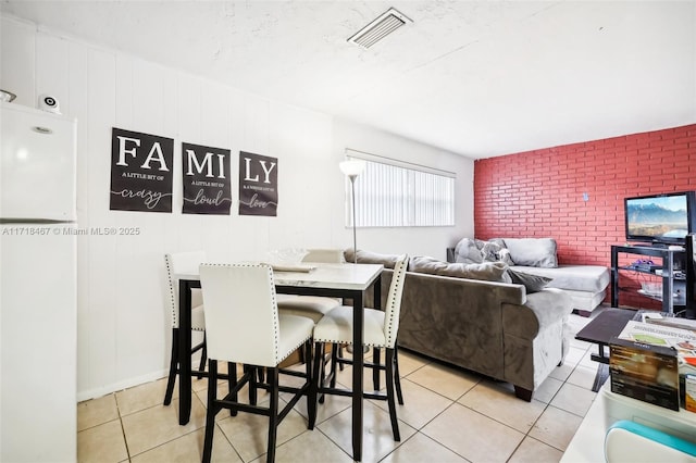 dining area with light tile patterned floors and brick wall