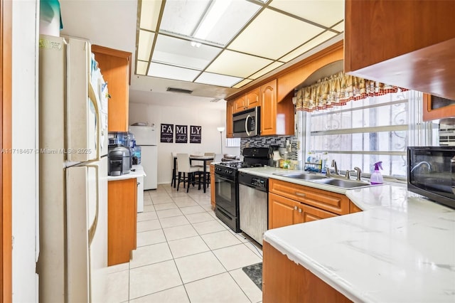 kitchen featuring backsplash, sink, light tile patterned floors, and stainless steel appliances