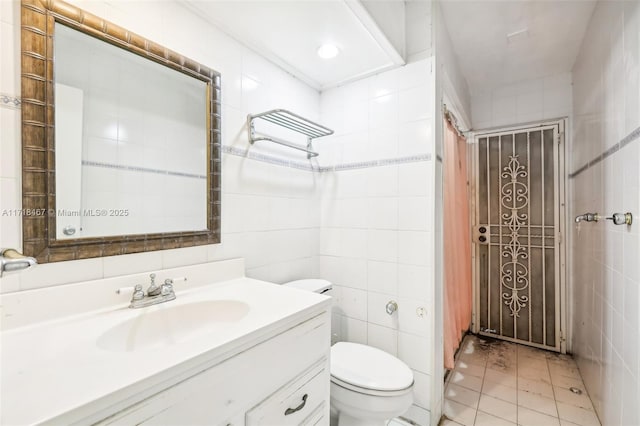 bathroom featuring tile patterned flooring, vanity, toilet, and tile walls