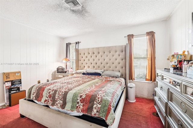 carpeted bedroom with wood walls, a textured ceiling, and multiple windows