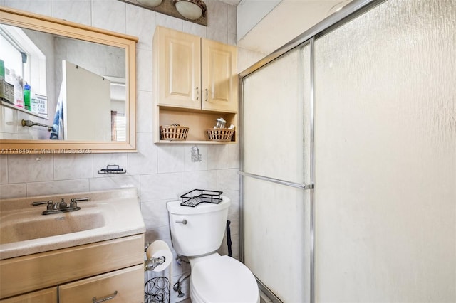 bathroom with vanity, a shower with door, toilet, and tile walls