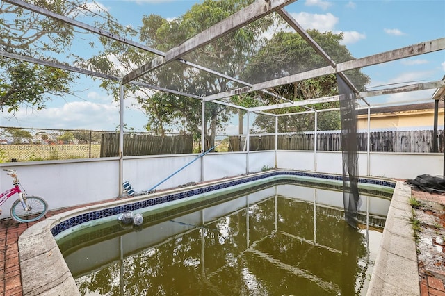 view of pool with glass enclosure and a water view