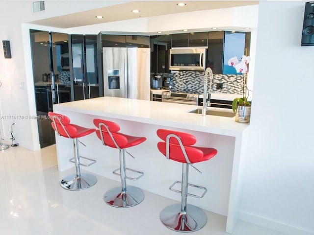 kitchen featuring sink, a kitchen bar, stainless steel appliances, and tasteful backsplash