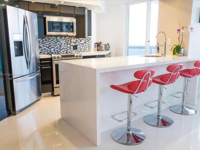 kitchen with decorative backsplash, a breakfast bar, stainless steel appliances, sink, and a water view