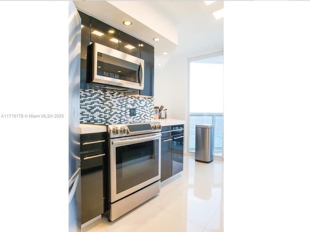 kitchen with tasteful backsplash, light tile patterned flooring, stainless steel appliances, and a water view