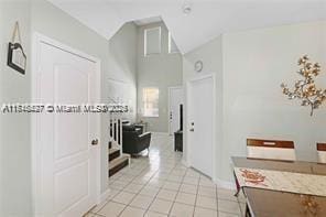 corridor with light tile patterned flooring and lofted ceiling